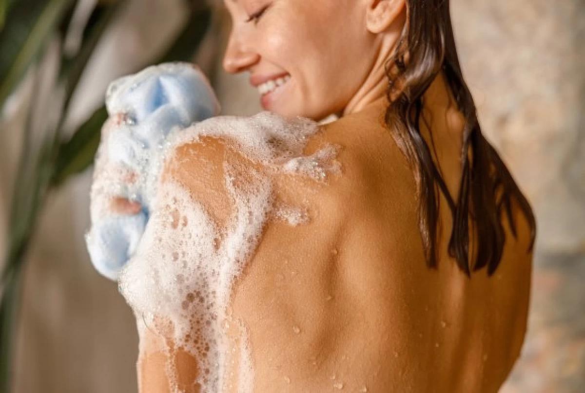 Une femme se douche avec un gel douche végane.