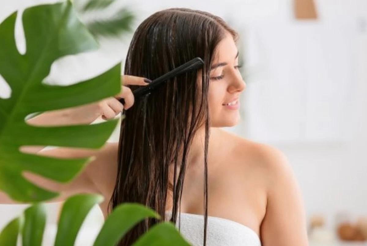 Woman applies vegan conditioner to herself with comb.