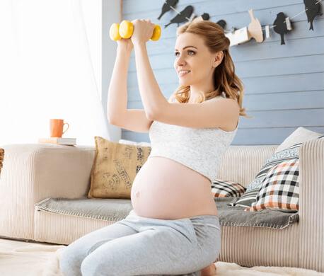 Pregnant woman trains with dumbbells